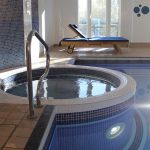 The jacuzzi and loungers in front of a window